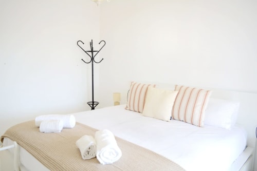 Bedroom with white bed, striped pillows, rolled towels, and decorative coat stand at Royal Banus, Marbella