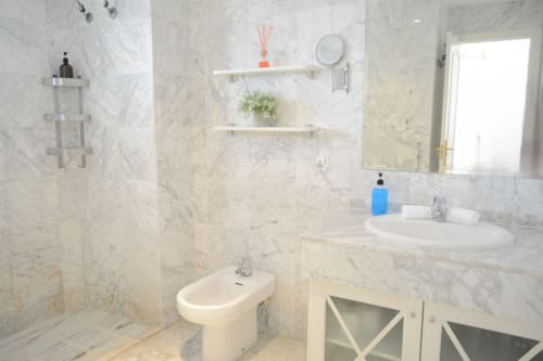 Luxurious marble bathroom at Royal Banus, Marbella with sink, bidet, shelving, and shower area