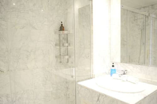 Modern marble bathroom at Royal Banus Marbella with glass shower enclosure, white vanity sink, and mirror