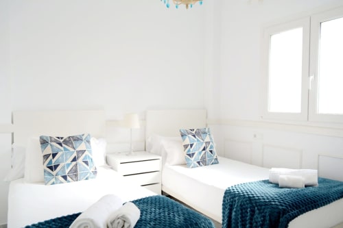 Twin beds with geometric blue pillows in bright Marbella beachfront apartment at Royal Banus