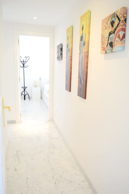 Modern hallway at Royal Banus Marbella with colorful artwork and marble flooring leading to bright rooms