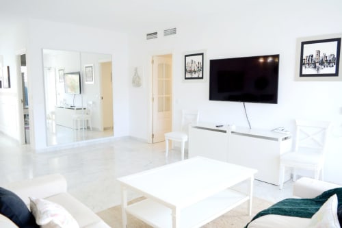 Modern living room at Royal Banus in Marbella with white furniture, flat-screen TV, and marble flooring.