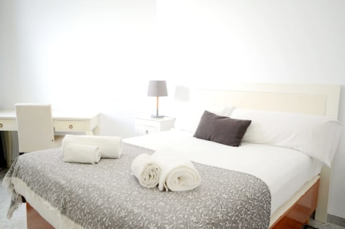 Modern bedroom at Royal Banus with rolled towels, gray bedding, and beachfront mountain views in Marbella