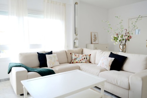 Bright living room with cream sectional sofa, colorful pillows, and white coffee table at Royal Banus in Marbella