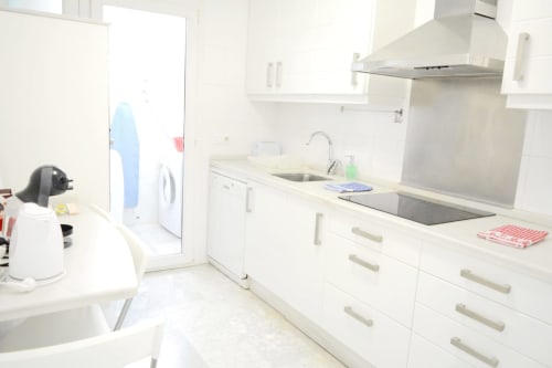 Modern white kitchen in Royal Banus apartment, Marbella, featuring stainless steel appliances and countertops