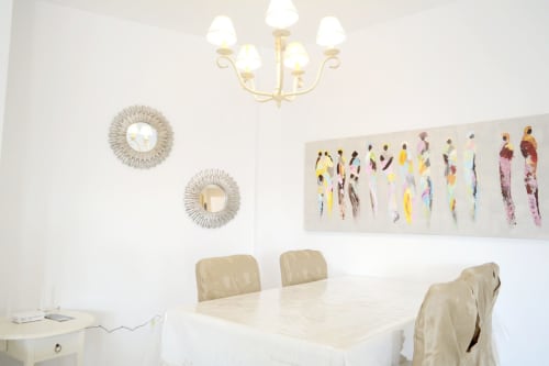 Elegant dining room at Royal Banus Marbella with cream chairs, marble table, sunburst mirrors, and colorful abstract artwork