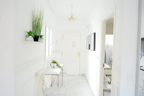 Bright hallway in Royal Banus Marbella apartment with white walls, potted plants, and access to laundry area and rooms