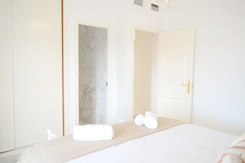 Modern bedroom mirror in Royal Banus apartment, Marbella, with white towels and open doors to ensuite bathroom