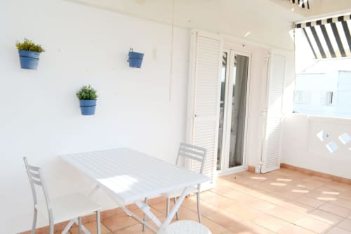Bright terrace at Royal Banus Marbella with white dining table, blue hanging planters, and lounge seating overlooking the