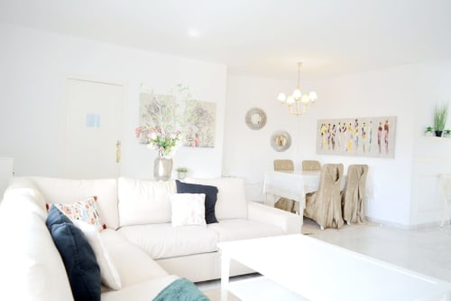 Bright modern living room in Royal Banus Marbella with white sofa, dining area, contemporary artwork, and coastal design