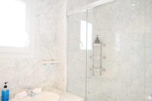 Modern marble-tiled shower enclosure with glass partition in Royal Banus beachfront apartment, Marbella