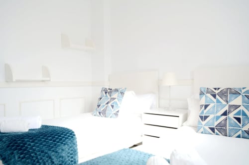 Modern bedroom at Royal Banus Marbella with blue geometric pillows, white bedding, and coastal-inspired decor overlooking the