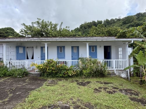 Bungalow créole blanc aux portes bleues à Habitation La Reine Du Camp, Saint Claude, entouré de jardins tropicaux
