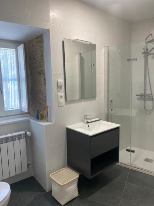 Baño moderno en Pensión A Casiña d'avoa en Osera con mueble negro, ducha de lluvia y toallero calefactor