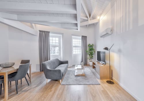 Modern duplex apartment living room at Oporto Comfort Dom Hugo, Porto with gray sofa, wooden floors, and city views