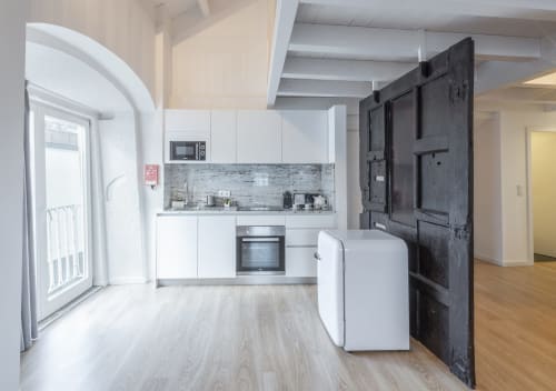 Modern kitchen and living area in Porto BnB apartment with white cabinetry, stainless steel appliances, and wooden flooring
