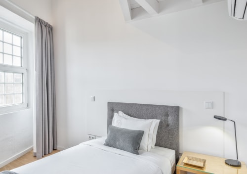 Modern bedroom at Oporto Comfort Dom Hugo Porto with gray headboard, white bedding, and city view window