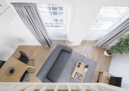 Overhead view of modern Porto apartment with gray sofa, wooden floors, skylights, and city views at Oporto Comfort Dom Hugo
