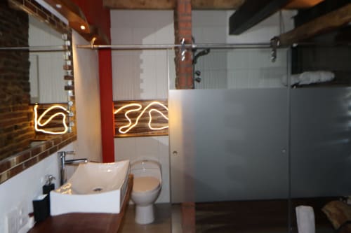 Baño moderno en el hotel Casa Acento, Valle de Bravo, con letrero de neón, lavamanos tipo recipiente, inodoro y ducha de cristal