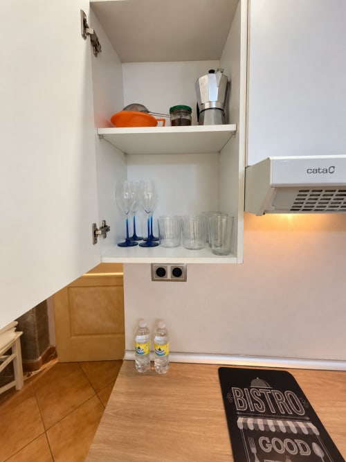 Armario de cocina con vasos, cafetera moka y utensilios en el apartamento Peperete, Baiona