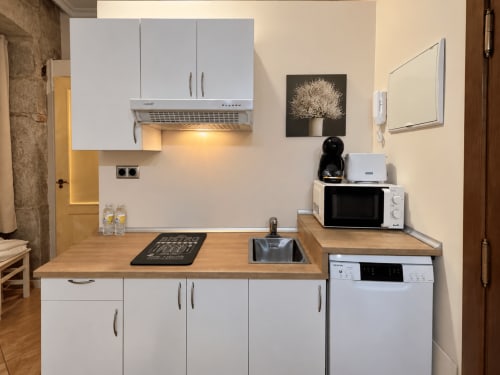 Cocina blanca moderna en loft de Baiona con encimera de madera, electrodomésticos y microondas en estante superior