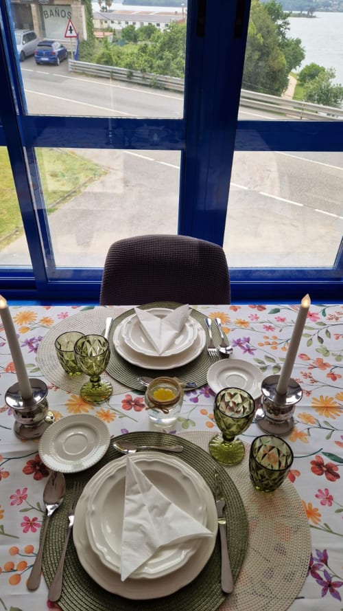 Elegante comedor en Houses by Pilar con vistas al mar, mesa formal con platos blancos y cristalería verde