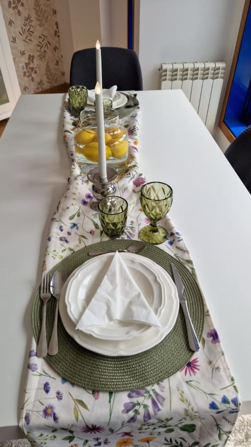 Elegante servicio de comedor formal en Houses by Pilar con camino floral, vajilla blanca, copas verdes y vela encendida