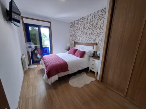 Dormitorio moderno en Houses by Pilar, Sotomayor con vista al mar, cama queen, detalles rosa, piso de madera y acceso a balcón