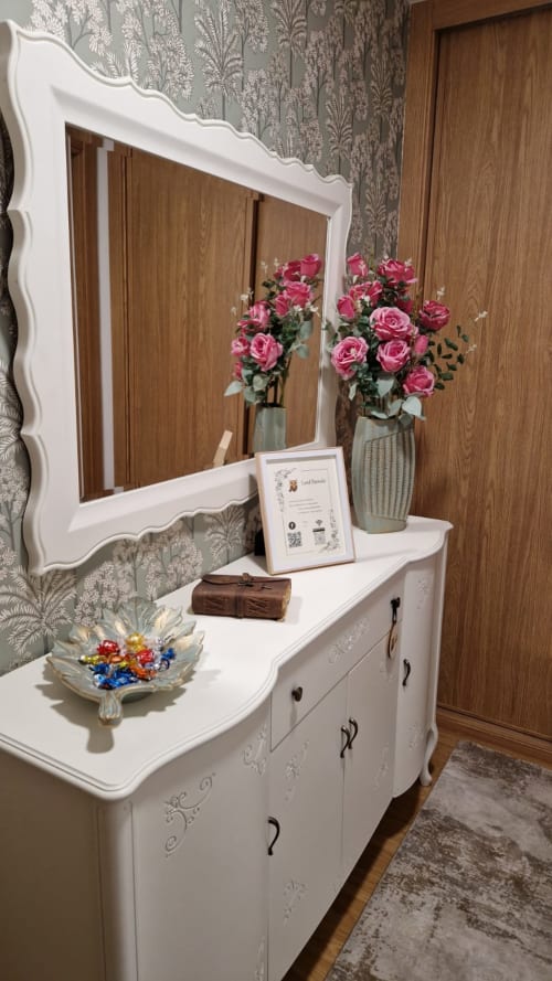 Elegante tocador blanco con espejo ornamentado, rosas rosadas en florero y accesorios decorativos en apartamento Lord Parrulo de Houses