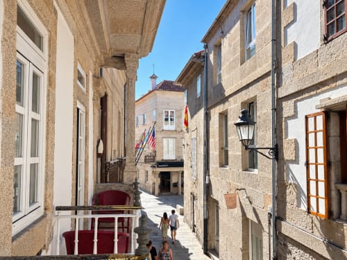 Encantadora calle adoquinada en el casco antiguo de Baiona con edificios de piedra, puertas coloridas y arquitectura histórica