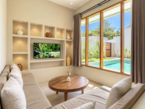 Moderna sala de villa con TV de pantalla plana, estantes integrados y ventanales que dan a la piscina