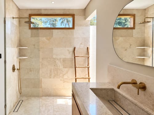 Lujoso baño en Oasis Dune Villas con ducha de mármol, pisos climatizados y espejo arqueado con vistas a jardines tropicales