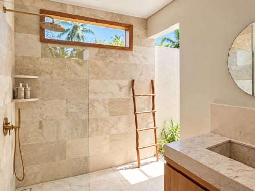 Baño de concepto abierto lujoso en Oasis Dune Villas con baldosas de mármol, ducha de cristal, escalera de madera y vistas tropicales