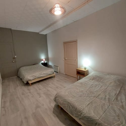 Chambre double de l'appartement Les Hortensias à Bourbonne-les-Bains avec lits, tables de nuit et équipements modernes