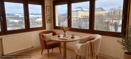 Coin salon cosy du gîte Les Hortensias à Champlitte avec fauteuils, table ronde et vue sur le jardin du château
