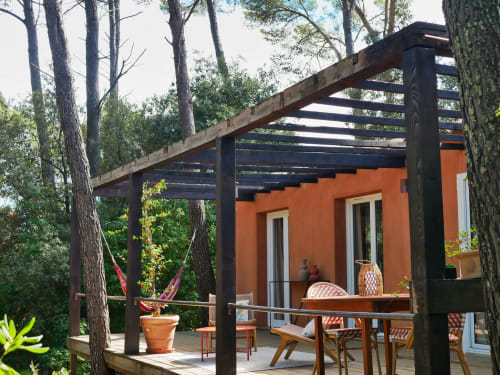 Terrasse du Lodge aux Terrasses de Lorgues avec pergola, bâtiment orange, vue sur le jardin et espace détente