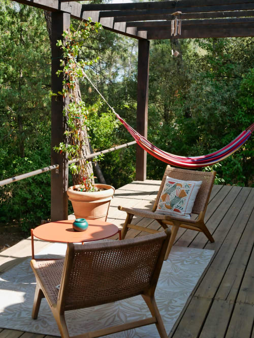 Terrasse ombragée aux Terrasses de Lorgues avec fauteuils en osier, hamac rouge et vue sur le jardin à Lorgues, France