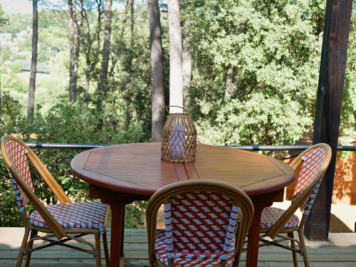 Terrasse de dining en plein air aux Terrasses de Lorgues avec table ronde en bois, chaises à motifs et vue sur la forêt