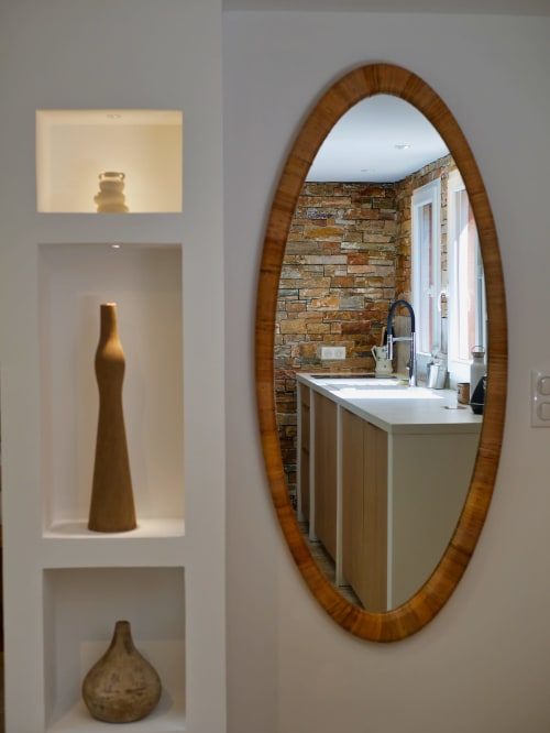 Salle de bain moderne aux Terrasses de Lorgues avec miroir à cadre bois, mur en pierre et vases décoratifs