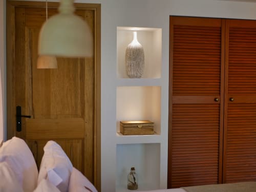 Chambre Le Lodge aux Terrasses de Lorgues avec portes en bois, étagères murales décorées d'objets d'art et éclairage chaleureux.