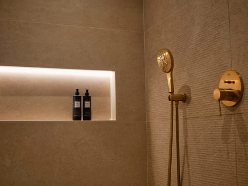 Salle de bain moderne avec robinetterie en laiton et carrelage texturé dans la chambre Le Lodge aux Terrasses de Lorgues