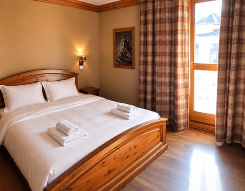 Chambre luxueuse avec vue montagne au Chalet des Cimes, lit en bois, linge blanc et vue sur les Alpes de la Plagne