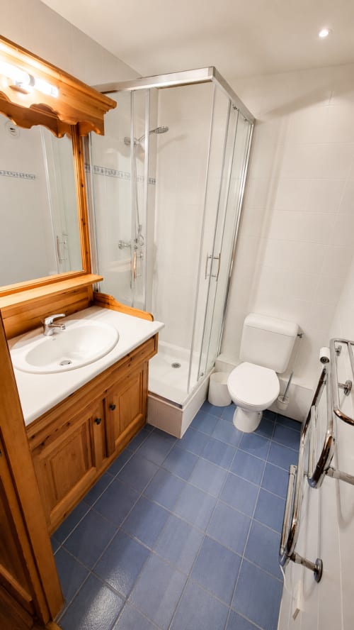 Salle de bain moderne de l'appartement Le Chalet des Cimes avec meuble-lavabo en bois, douche et carrelage bleu à Belle Plagne