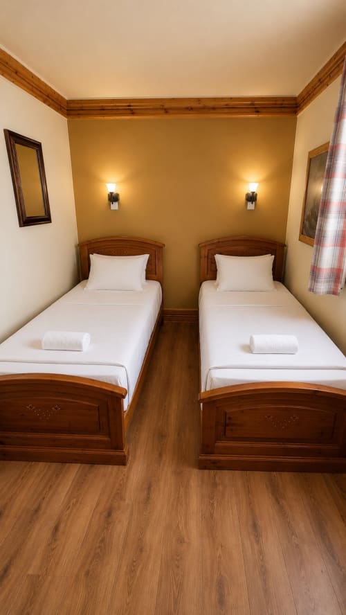 Chambre twin du Chalet des Cimes à Belle Plagne avec lits en bois, murs dorés chauds et parquet