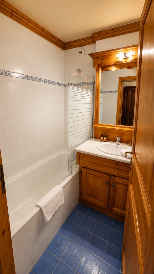 Salle de bain avec vanité en bois, carrelage blanc et sol bleu au Chalet des Cimes, Belle Plagne