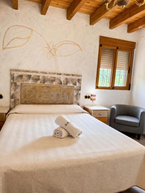 Serranía hotel standard room in Chulilla with king-size bed, wooden beams, garden view window, and modern amenities