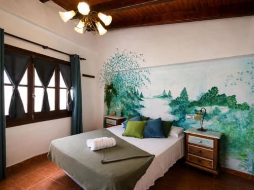 Spacious double room with garden view mural, wooden furniture, and nature-themed décor at Serranía hotel in Chulilla