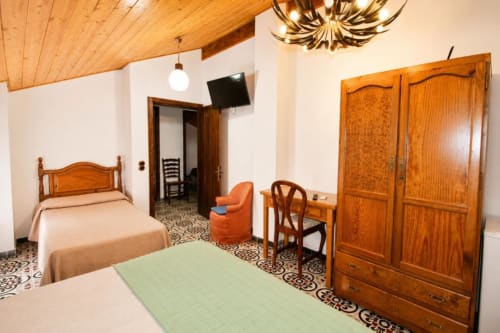 Triple room at Serranía hotel in Chulilla with wooden furniture, tiled floor, TV, and garden views