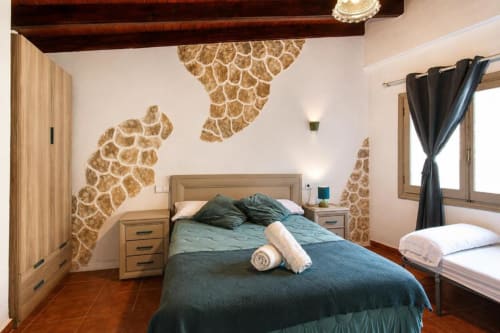 Triple Room at Serranía hotel in Chulilla with twin bed, giraffe-pattern wall art, wooden beams, and terracotta flooring