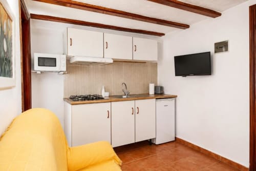 Modern kitchen and living area in Standard Apartment at Serranía Gestión Turística, Chulilla with white cabinetry, cooktop,